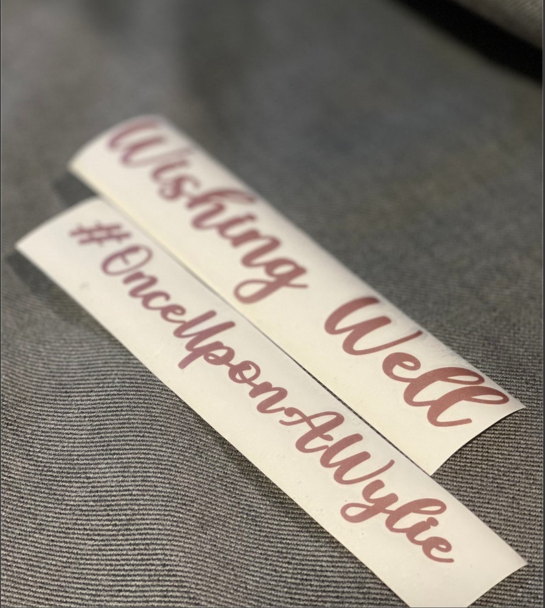 May include: Two white vinyl stickers with pink lettering. The top sticker says "Wishing Well" and the bottom sticker says "#OnceUponATime".