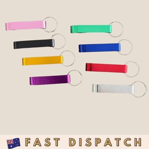 May include: A selection of keyrings in a range of colours: pink, green, black, blue, yellow, red, purple, and silver. Each keyring has a rectangular metal bar attached to a silver ring.