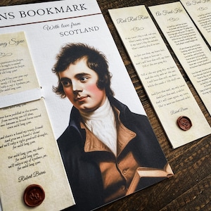 May include: A collection of paper bookmarks featuring the portrait of Robert Burns, printed poems including Auld Lang Syne and Red Red Rose, and decorative red wax seals. The set is titled BURNS BOOKMARK and includes the text With love from SCOTLAND.
