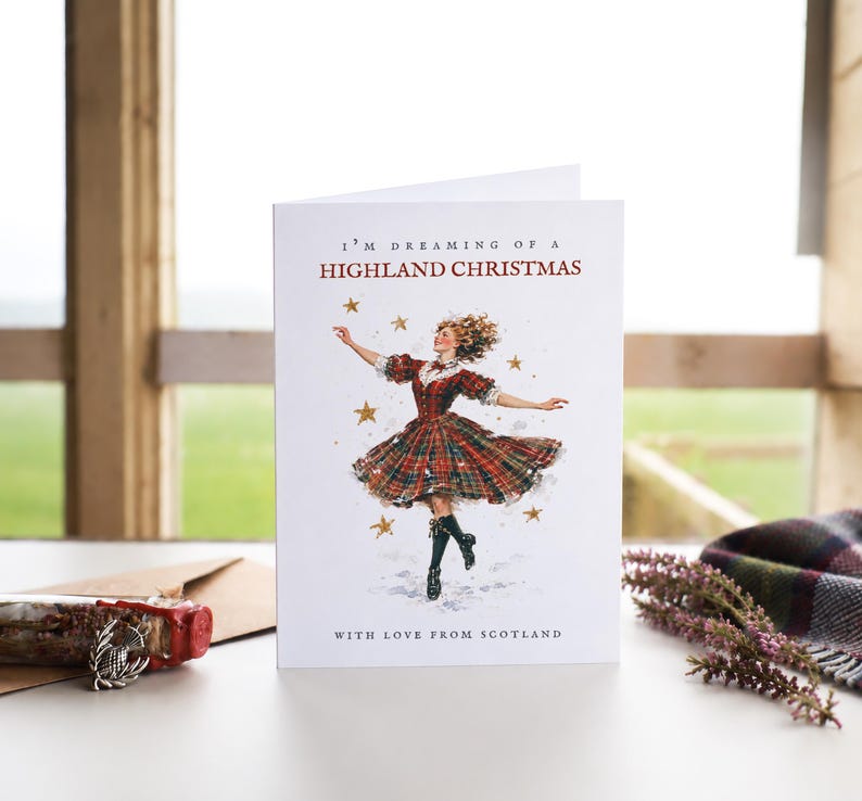 Pu&ograve; includere: Un biglietto d'auguri bianco con il testo I'M DREAMING OF A HIGHLAND CHRISTMAS e WITH LOVE FROM SCOTLAND. L'illustrazione mostra una persona con un abito scozzese rosso e verde che danza tra stelle dorate su uno sfondo bianco.
