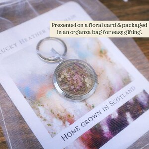 Pode incluir: Um porta-chaves prateado com um pendente redondo preenchido com flores rosa secas. O porta-chaves &eacute; apresentado num cart&atilde;o floral e embalado numa bolsa de organza. O texto "HOME GROWN IN SCOTLAND" &eacute; vis&iacute;vel.