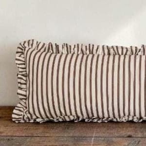 May include: A rectangular throw cushion featuring a pattern of vertical dark brown stripes on a cream-coloured background. The cushion is finished with a gathered ruffle trim along the edges, creating a textured border around the entire rectangular shape.