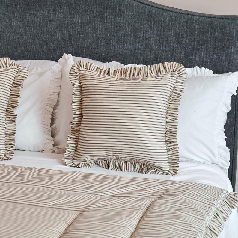 May include: A bed with a gray headboard and white bedding. The pillows and comforter feature a brown and white striped pattern. The pillows have ruffled edges.