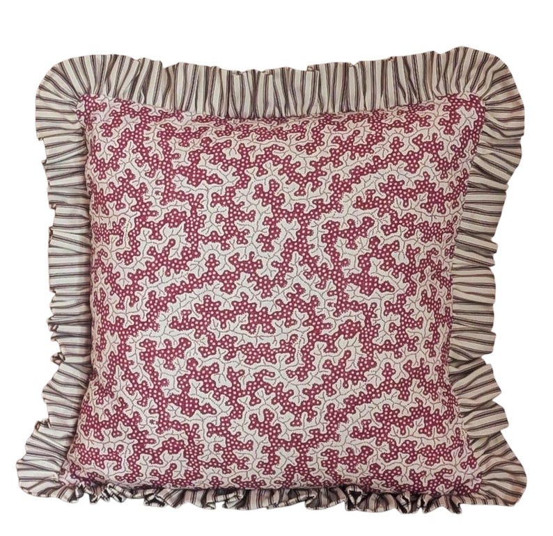 May include: Square decorative pillow with a white background and a repeating pattern of burgundy coral-like shapes. The pillow has a ruffled border with a striped pattern in shades of gray and white.