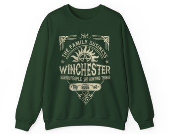Könnte beinhalten: Grünes Sweatshirt mit einem Vintage-Grafikdruck mit dem Text "The Family Business Winchester Saving People and Hunting Things Since 2005" und einem stilisierten Symbol mit einem Pentagramm und einer Sonne.