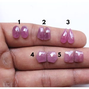 Könnte beinhalten: Fünf Paare rosa facettierter Edelstein-Cabochons, von 1 bis 5 beschriftet. Jedes Paar hat eine andere Form, darunter oval, quadratisch, tropfenförmig und sechseckig.