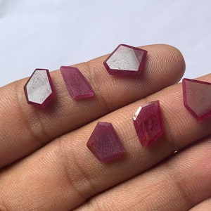 May include: Five faceted ruby gemstones in various shapes and sizes. The gemstones are a deep red colour and have a polished finish.