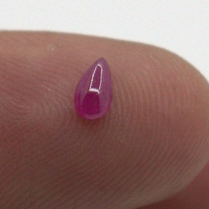 May include: A teardrop-shaped, pink gemstone with a smooth, polished surface.