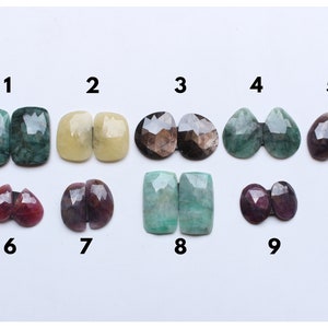Könnte beinhalten: Neun Paare von Edelstein-Cabochons, nummeriert von 1 bis 9. Die Cabochons sind in verschiedenen Farben, darunter Grün, Gelb, Braun und Lila.