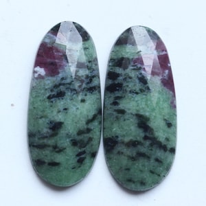 Può includere: Due pietre preziose ovali con una superficie sfaccettata. Le pietre presentano un mix di colori verdi, neri e marroni. Le pietre preziose lucide hanno una superficie liscia, ideali per la creazione di gioielli.