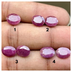 Puede incluir: Seis rubíes de color rojo rosáceo, tallados en forma ovalada y facetados, dispuestos en cuatro grupos numerados. Las piedras preciosas muestran una calidad translúcida con inclusiones internas visibles y una superficie pulida, con una forma ovalada clásica.