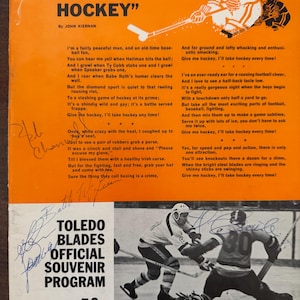 May include: Vintage Toledo Blades Official Souvenir Program from 1969-1970, featuring hockey action illustrations and the text "I'll Take Hockey" by John Kiernan. The cover is orange with black and white images and text.