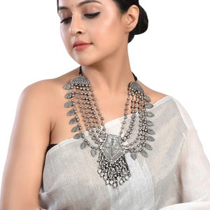 May include: A silver necklace with multiple strands of beads and decorative pendants. The necklace features a large, ornate pendant in the center.