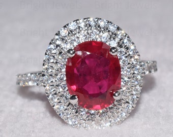 May include: A ring with a large oval-shaped ruby surrounded by a double halo of smaller diamonds.