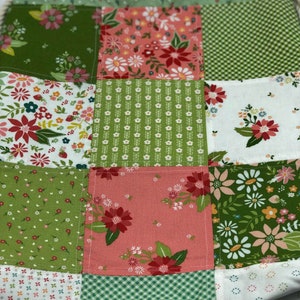 May include: A green and pink patchwork drawstring bag with a floral pattern. The bag is made of fabric and has a drawstring closure.