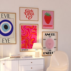 May include: A collection of framed art prints with various designs. One print features a large blue eye, another reads "Girls Don't Cry," and a third displays a strawberry. Other prints include abstract patterns and the word "ANGEL."