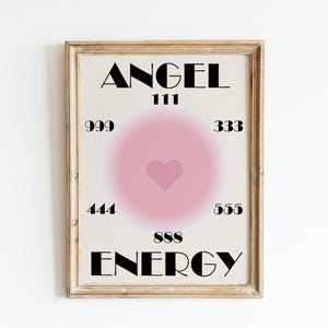 May include: A framed print with a pink heart in the center and the words "ANGEL ENERGY" in black text. The numbers 111, 999, 333, 444, 555, and 888 are arranged around the heart.