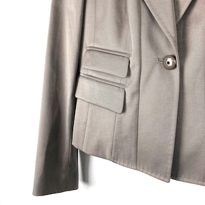 May include: A brown blazer with a single button closure and a flap pocket on the left side.