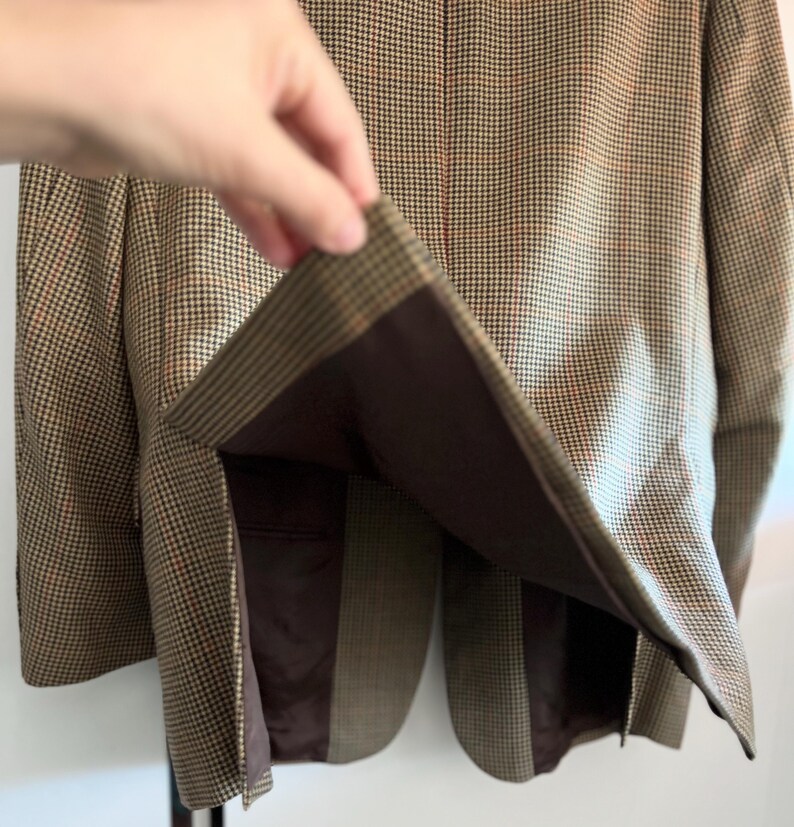 May include: A brown and tan plaid blazer with a brown lining. The blazer is unbuttoned and the lining is visible.