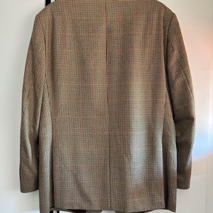 May include: A brown, black, and white patterned blazer. The blazer has a single button closure and a notched lapel.