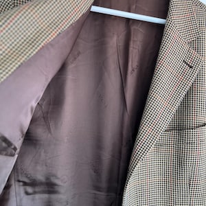 May include: A brown and tan plaid blazer with a brown lining. The lining has the words "Giorgio Armani" repeated in a pattern.