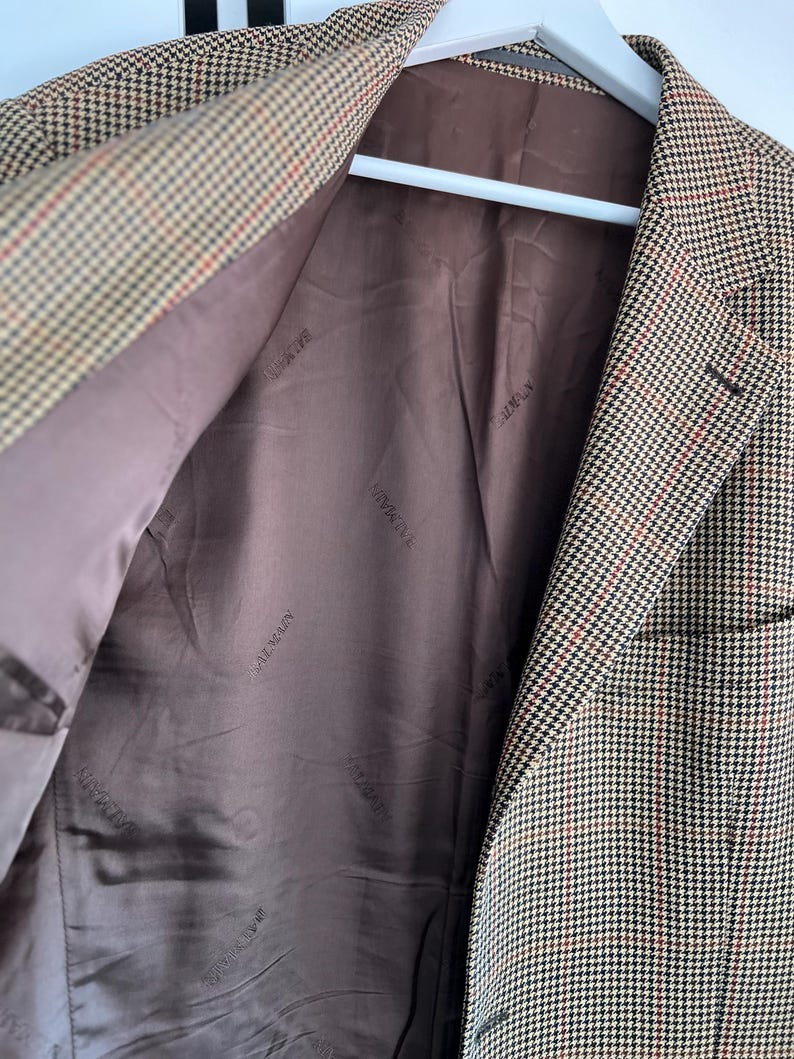 May include: A brown and tan plaid blazer with a brown lining. The lining has the words "Giorgio Armani" repeated in a pattern.