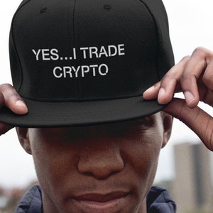 May include: A black baseball cap with a white embroidered message that reads "YES...I TRADE CRYPTO".