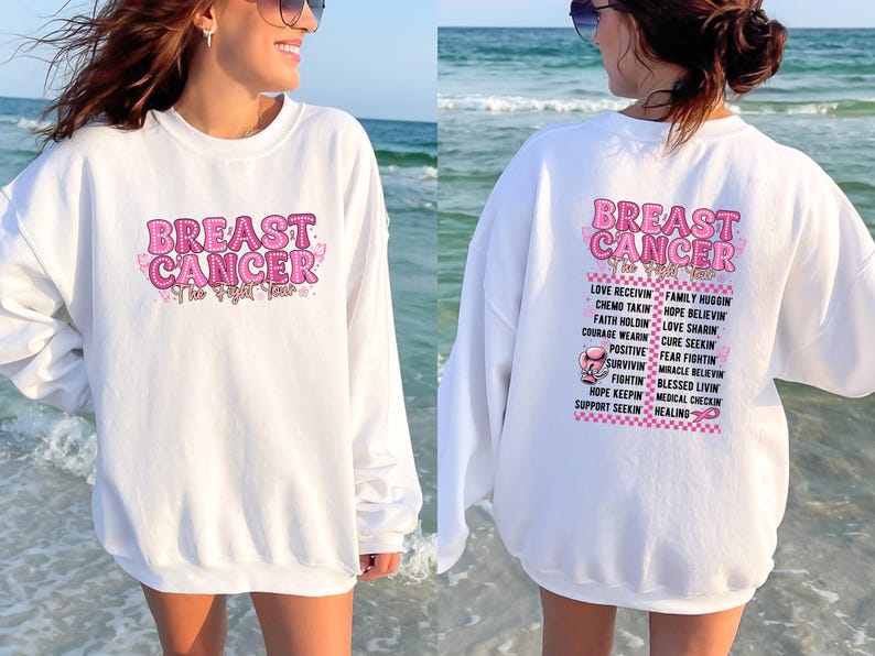Pu&ograve; includere: Felpa bianca con le parole "BREAST CANCER" in rosa, con un nastro rosa e un design a farfalla. La parte posteriore della felpa presenta un elenco di parole e frasi di supporto in rosa.