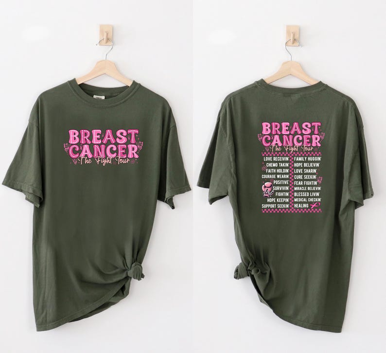 Pu&ograve; includere: Due magliette verde oliva con testo rosa. Una maglietta ha "BREAST CANCER The Fight Tour" sul davanti. L'altra ha lo stesso testo sul retro, insieme a un elenco di parole correlate.