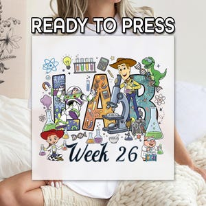 May include: A white square design with the words "READY TO PRESS" at the top. The design features the word "LAB" with cartoon characters and science-themed illustrations. Below, the text "Week 26" is written in cursive.