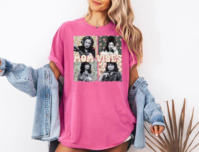 May include: Pink t-shirt with a graphic print of four women with the text "MOM VIBES" in a retro font.