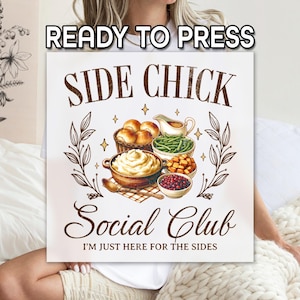 May include: A square, off-white sign with the words "READY TO PRESS" at the top. The sign features the text "SIDE CHICK Social Club" with an illustration of various side dishes. The phrase "I'M JUST HERE FOR THE SIDES" is at the bottom.