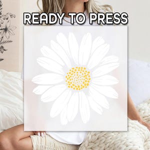 May include: A white daisy with a yellow center, ready to be pressed onto a t-shirt or other fabric. The image is on a white background.