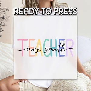 May include: White square with the text "READY TO PRESS" at the top. Below, the word "TEACHER" is written in colorful block letters, with "mrs. smith" in cursive underneath. The design is likely for a teacher.