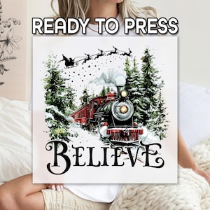 May include: A square canvas print with a Christmas theme. The image features a red and black steam train in a snowy forest, with Santa's sleigh and reindeer above. The word "BELIEVE" is written in large letters. The text "READY TO PRESS" is at the top.