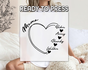 May include: White t-shirt with a black heart design and the text "Mama" above the heart. Inside the heart are the names "Baker", "Avery", "Shandy", and "Walker" with a small heart next to each name.