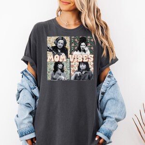 May include: A dark gray t-shirt with a graphic print of four women with floral accents and the text "MOM VIBES".