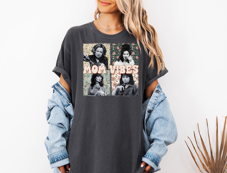 May include: A dark gray t-shirt with a graphic print of four women with floral accents and the text "MOM VIBES".