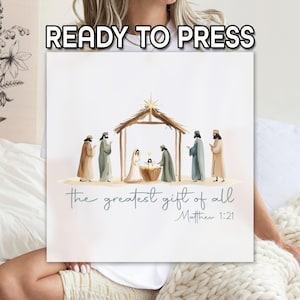 May include: A square canvas print featuring a watercolor illustration of the Nativity scene. The image includes the text "the greatest gift of all" and "Matthew 1:21". The words "READY TO PRESS" are at the top.