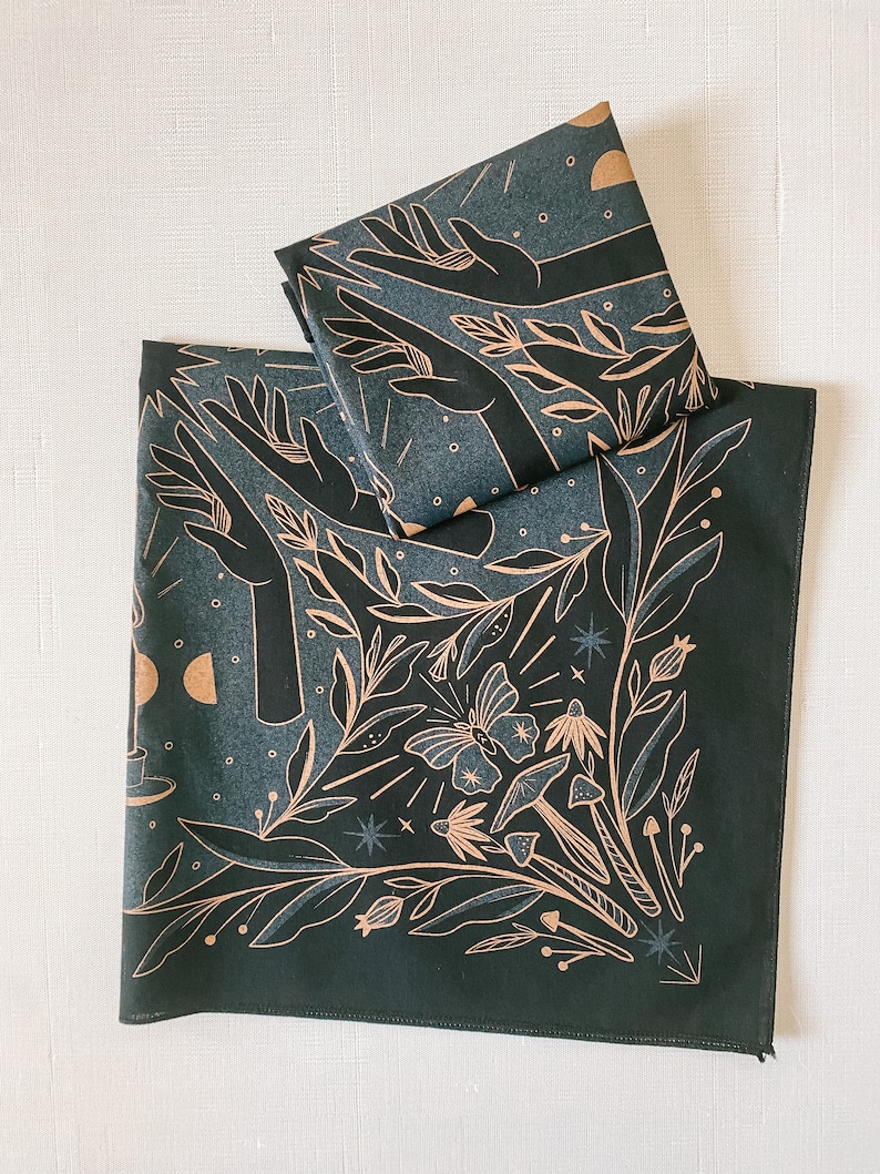 May include: Two dark green fabric bandanas with a gold print of hands reaching up, leaves, a butterfly, mushrooms, and stars.