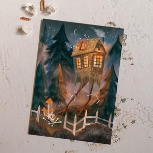 May include: An art print featuring a whimsical illustration of a house with long, spindly legs, set in a dark forest. The house has lit windows and a smoking chimney. A white picket fence and skull are in the foreground.