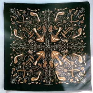 Op de afbeelding: Een zwarte bandana met een wit ontwerp van paddenstoelen en bladeren. De bandana heeft de tekst "LANTERN PRINT CO."