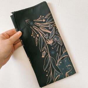 May include: A black bandana with a gold floral design. The design features leaves, flowers, and mushrooms.