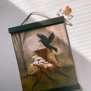 May include: A black crow flies over a tree stump with white mushrooms growing on it. The background is a dark forest with a full moon shining through the trees. The image is in a black frame.
