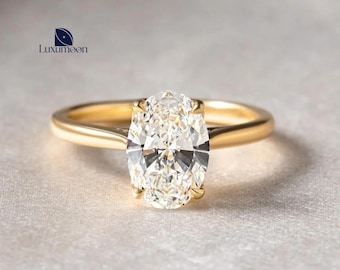 Può includere: Un anello d'oro con un diamante taglio ovale. Il diamante è tenuto da quattro griffe. La fascia è in oro liscio. L'anello è mostrato su una superficie strutturata. Un design classico per fidanzamenti o occasioni speciali.