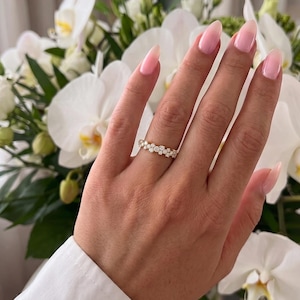 May include: A gold band ring featuring a cluster of small, round, clear stones arranged in a continuous, textured pattern across the top surface of the band, creating a sparkling, multi-faceted appearance on the finger.
