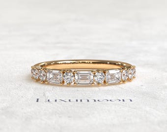 May include: A gold band ring featuring an alternating pattern of clear emerald-cut and round-cut stones set in a shared prong setting. The ring displays a polished gold finish and is positioned above the text Luxumoon printed in dark blue.