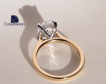 May include: A gold engagement ring with a round diamond set in a white gold setting. The ring is on a white background.