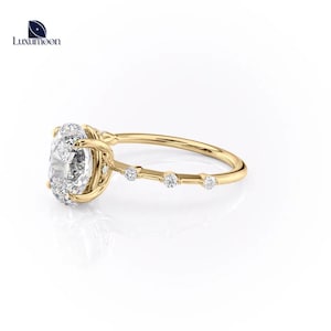 May include: A gold engagement ring featuring a large oval-shaped centre stone and smaller round stones set along the band.