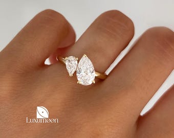 May include: A gold ring with two pear-shaped diamonds. The larger diamond is set on the top of the ring, and the smaller diamond is set on the side of the ring.